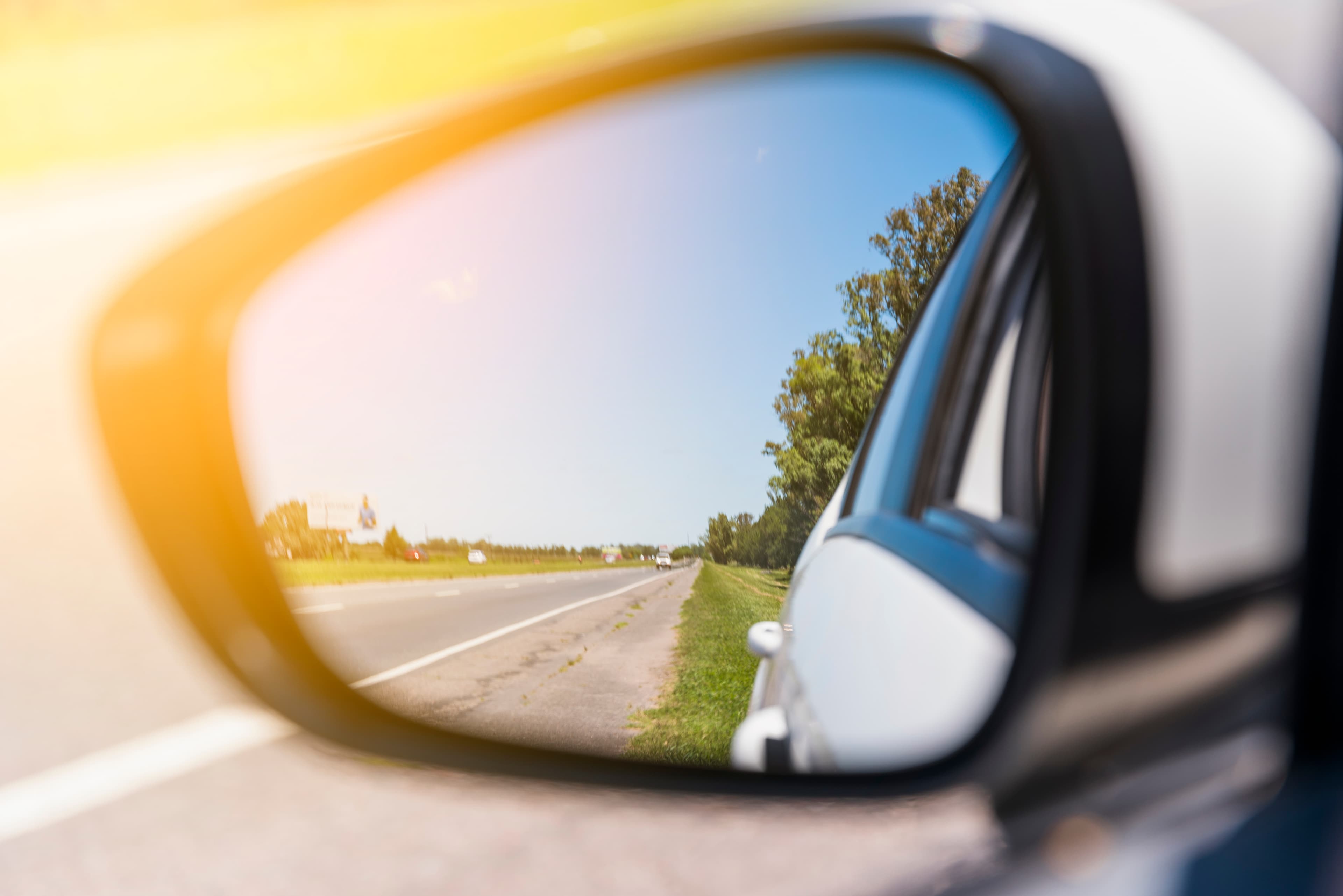 Road reflected in a side mirror — reflection and awareness.
